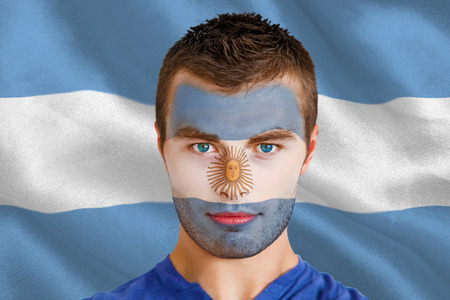 Composite image of serious young argentina fan with facepaint against argentinian flagの写真素材