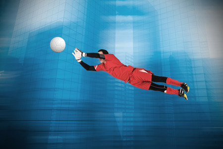 Fit goal keeper jumping up against urban sceneの写真素材