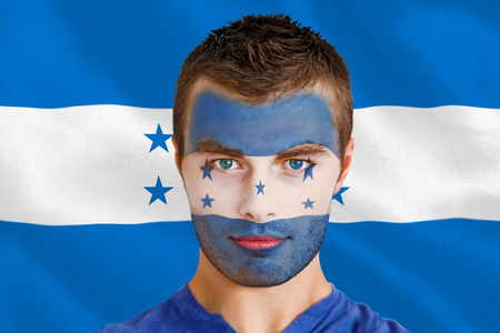 Composite image of serious young honduras fan with facepaint against digitally generated honduras national flagの写真素材