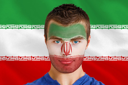 Composite image of serious young iran fan with facepaint against digitally generated iran national flagの写真素材
