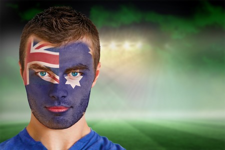 Composite image of australia football fan in face paint against football pitch under green sky and spotlightsの写真素材