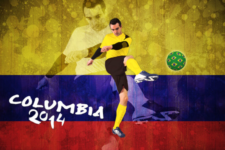Football player in yellow kicking against colombia flag in grunge effectの写真素材