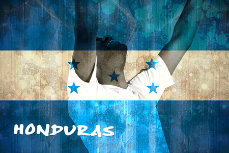 Excited handsome football fan cheering against honduras flag in grunge effectの写真素材