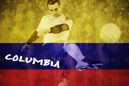 Football player in yellow kicking against colombia flag in grunge effectの写真素材