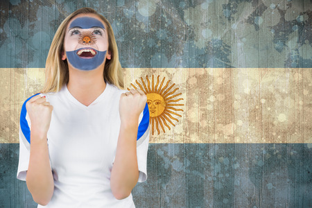 Excited argentina fan in face paint cheering against argentina flag in grunge effectの写真素材