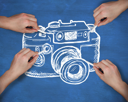 Composite image of multiple hands drawing camera with chalk against navy blueの写真素材