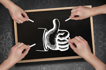 Composite image of multiple hands drawing thumb up with chalk against blackboardの写真素材