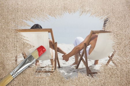 Composite image of couple on the beach in deck chairs with paintbrush dipped in red against weathered surface の写真素材