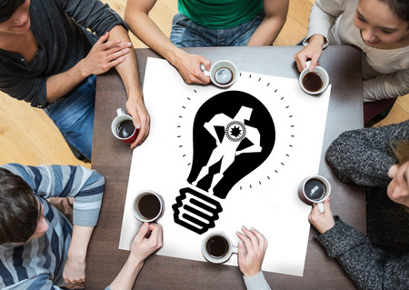 People sitting around table drinking coffee with page showing idea and innovation graphicの写真素材