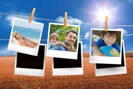 Composite image of instant photos hanging on a line against field and blue skyの写真素材