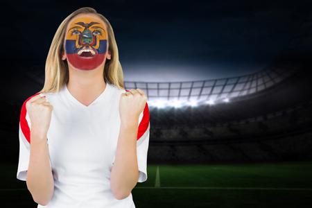 Excited ecuador fan in face paint cheering against large football stadium under night skyの写真素材
