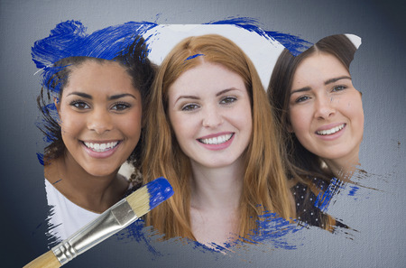 Composite image of pretty friends smiling at camera with paintbrush dipped in blue against digitally generated grey vignette backgroundの写真素材