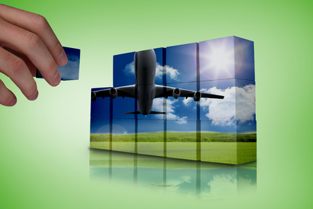 Hand building wall showing 3d plane taking off over grasslandの写真素材