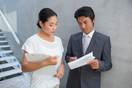 Estate agent showing lease to customer and smiling outside a houseの写真素材