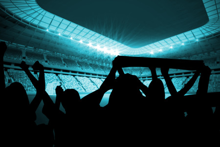 Silhouettes of football supporters against large football stadium with lightsの写真素材