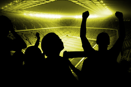 Silhouettes of football supporters against large football stadium with lightsの写真素材