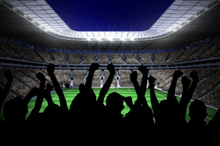 Silhouettes of football supporters against large football stadium with lightsの写真素材