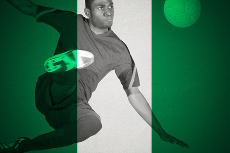 Football player in green kicking against nigeria national flagの写真素材