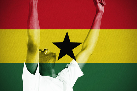 Excited handsome football fan cheering against ghana national flagの写真素材