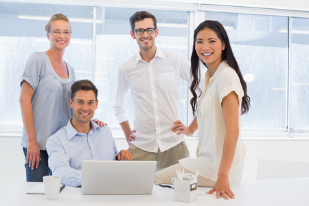 Casual business team smiling at camera at desk in the office