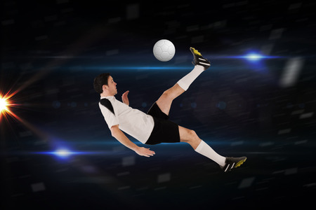 Football player in white kicking against black with sparkの写真素材