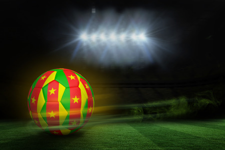Football in cameroon colours against football pitch under spotlightsの写真素材