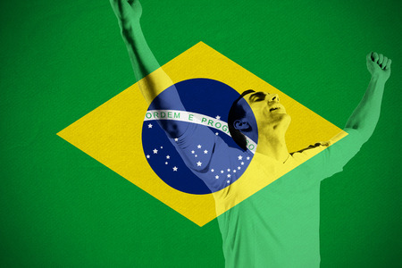 Excited football fan cheering against brasil national flagの写真素材