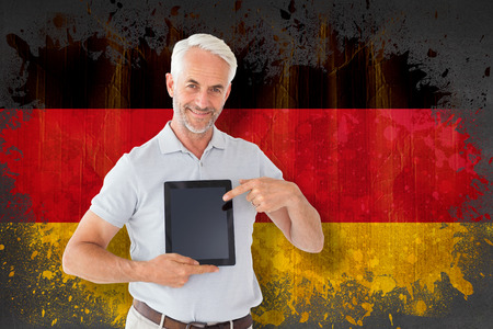 Mature student showing tablet pc against germany flag in grunge effectの写真素材