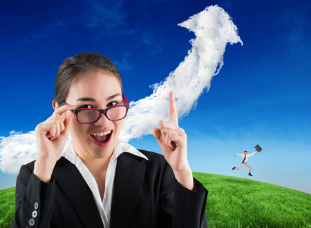 Cheerful jumping businessman with his suitcase against cloud arrowの写真素材