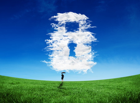 Composite image of young businesswoman holding umbrella against cloud lockの写真素材