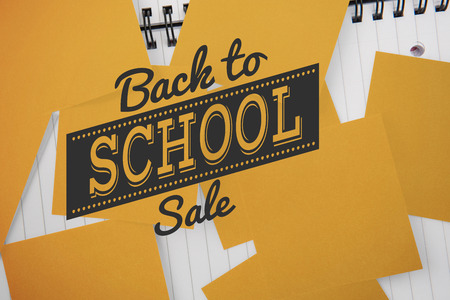 Back to school sale message against yellow paper strewn over notepadの写真素材