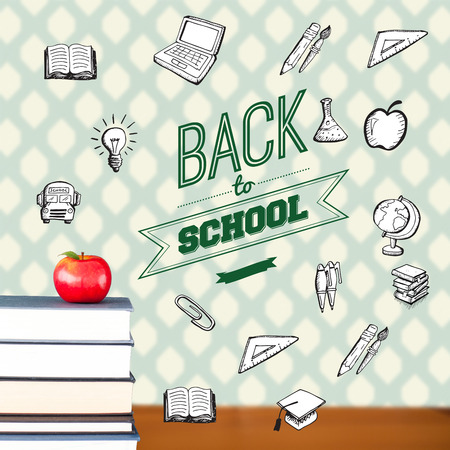 Back to school message with icons against red apple on pile of booksの写真素材