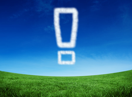 Cloud in shape of exclamation mark against green field under blue skyの写真素材