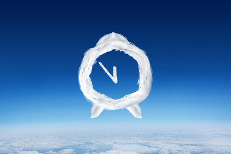Cloud alarm clock against blue sky over clouds at high altitudeの写真素材