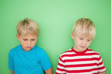 Sad little boys looking down on green backgroundの写真素材
