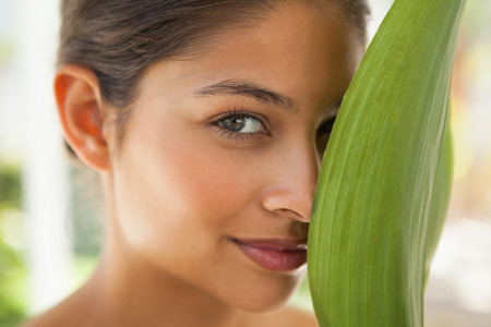 Beautiful brunette smiling with green leaf at the health spaの写真素材