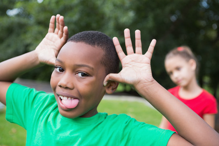 Cute little boy making silly faces outside in the parkの写真素材