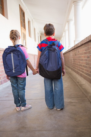 Cute pupils holding hands in corridor at the elementary schoolの写真素材