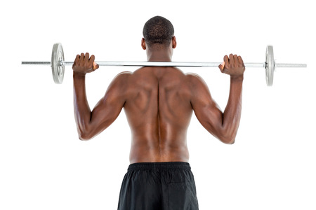 Rear view of a fit shirtless man lifting barbell over white background