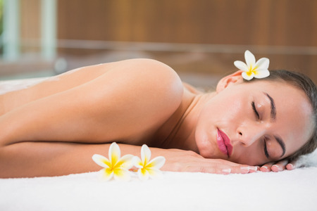 Side view of a beautiful young woman lying on massage table at spa centerの写真素材