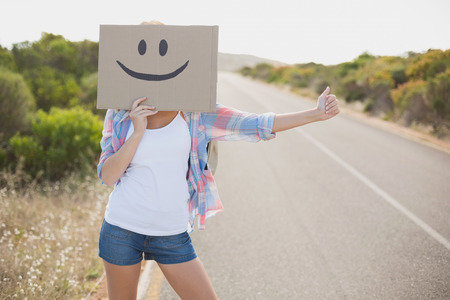 Portrait of a woman with smiley face hitchhiking on countryside roadの写真素材