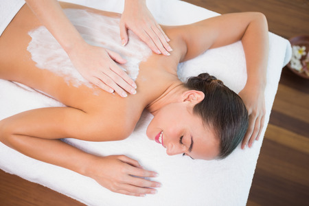 High angle view of an attractive young woman receiving back mask cream at spa centerの写真素材