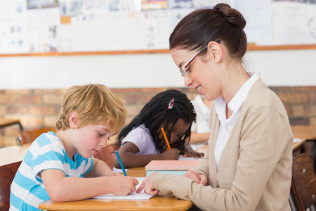 Pretty teacher helping pupil in classroom at the elementary schoolの写真素材