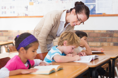 Pretty teacher helping pupil in classroom at the elementary schoolの写真素材