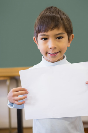 Cute pupil smiling at camera in classroom showing page at the elementary schoolの写真素材