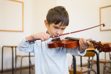 Cute pupil playing violin in classroom at the elementary schoolの写真素材