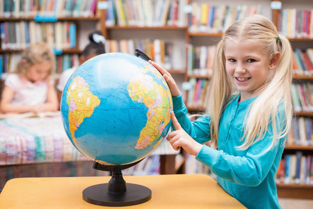 Cute pupil looking at globe in library at the elementary schoolの写真素材