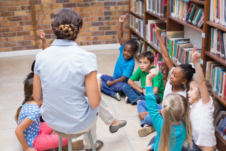 Cute pupils and teacher having class in library at the elementary schoolの写真素材