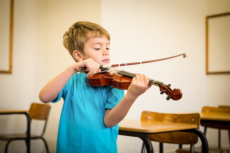 Cute pupil playing violin in classroom at the elementary schoolの写真素材