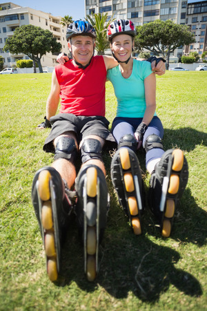 Fit mature couple wearing roller blades on the grass on a sunny dayの写真素材